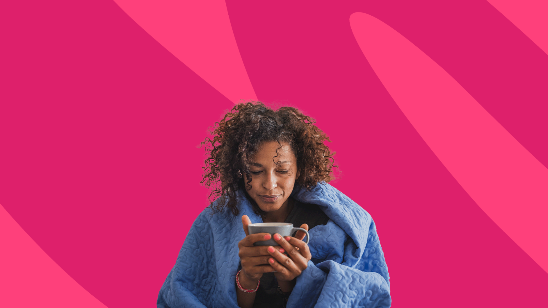 Person huddled in blanket with mug