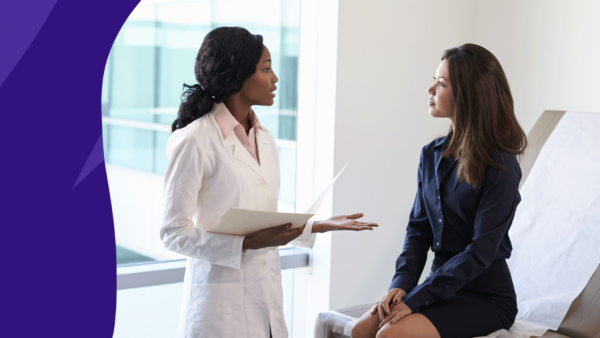 Healthcare provider talking to female patient in exam room: Brown discharge mid-cycle