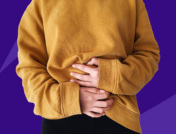 A person wearing a sweatshirt and holding their hands to their stomach