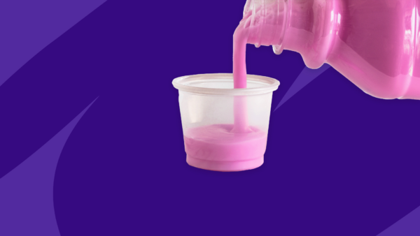 A bottle of pink liquid being poured into a medicine cup: OTC antiemetic medications