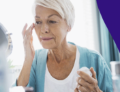 An older adult touching the area near their eye and looking in the mirror: Skin tag on eyelid