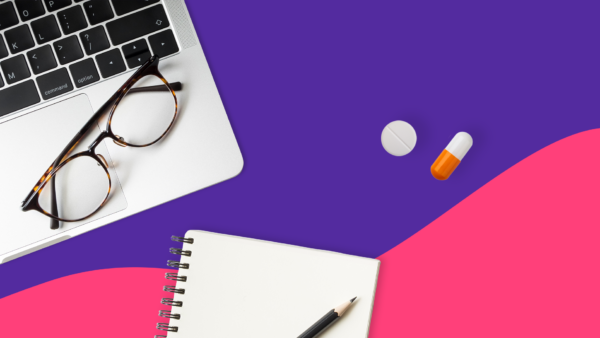 An open laptop with eyeglasses lying on it, a notepad, and a couple of pills: Does Medicare cover Ozempic?