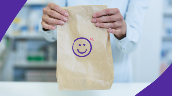 A pharmacist holding a prescription bag that has a smiley face on it: Nurtec copay card: Save on migrain medication
