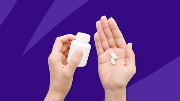One hand holding a pill bottle and another hand open with two pills in it: Rexulti generic availability, cost, and more