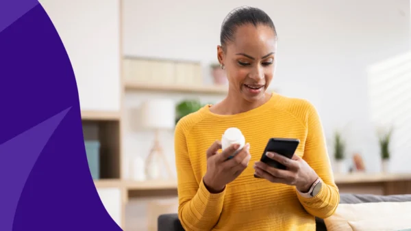 A woman looking at a pill bottle and her phone | How long does Farxiga stay in your system