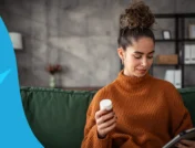 A woman looking at a tablet and her pill bottle | amitriptyline for nerve pain