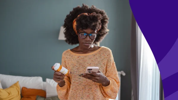 A woman looking at her phone and a pill bottle | How soon after taking prednisone can I take ibuprofen?