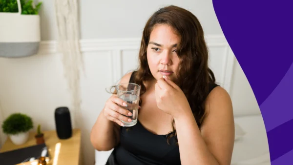 A woman taking a piill | Does prednisone make you sweat?