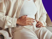 A woman holding her abdomen | Does metformin cause constipation?