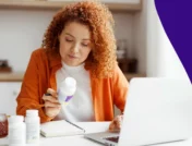 A woman looking at pill bottles | Medications that cause cold intolerance