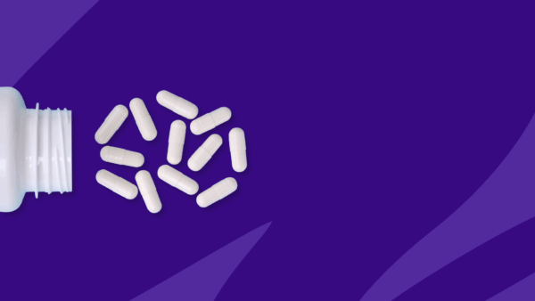 White capsules spilling out of a pill bottle: How much does Vraylar cost per month?