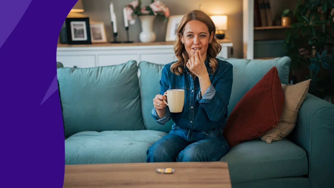 Woman sitting on her couch taking a pill with a cup of coffee - coffee and warfarin