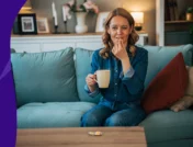 Woman sitting on her couch taking a pill with a cup of coffee - coffee and warfarin