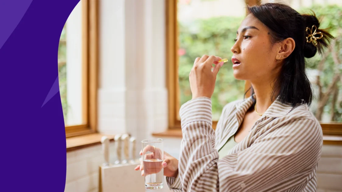 A woman taking a supplement | Does vitamin D cause constipation?