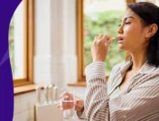 A woman taking a supplement | Does vitamin D cause constipation?