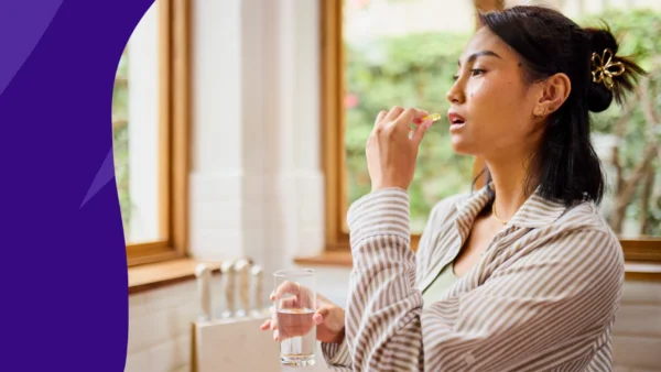 A woman taking a supplement | Does vitamin D cause constipation?