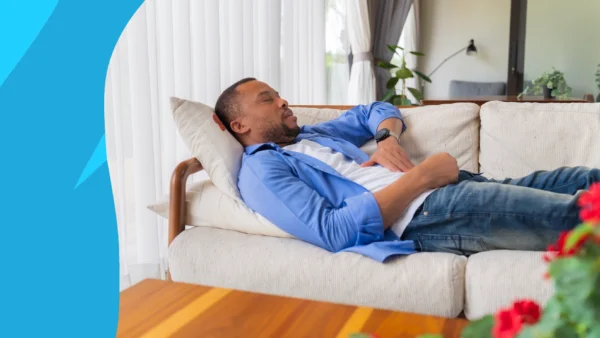 man laying down on the couch - Do statins make you tired?