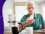 older adult holding a pill bottle and looking at a pot of coffee - why can't you have caffeine with farxiga