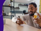 A man looking at his phone and a prescription bottle | How long does lisinopril stay in your system?