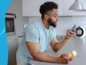 A man looking at a pill bottle and his phone | Does lisinopril cause ED?