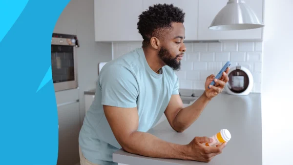 A man looking at a pill bottle and his phone | Does lisinopril cause ED?