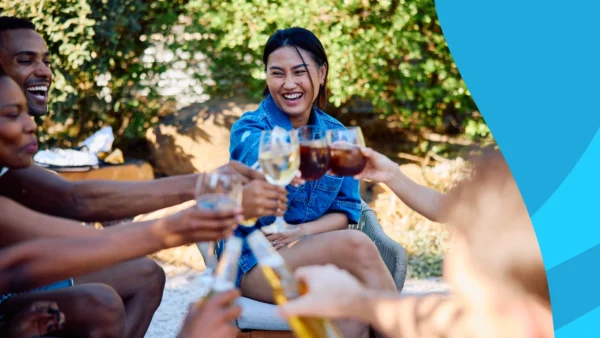 Image of several people sitting on a picnic blanket clinking glasses of wine at a park to represent "Do Losartan and alcohol mix?"