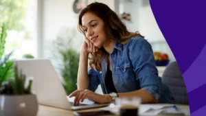 Woman sitting at a desk on her laptop and smiling to represent SingleCare August Trustpilot reviews