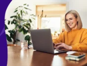 Image of a woman looking at her computer reading SingleCare Trustpilot reviews