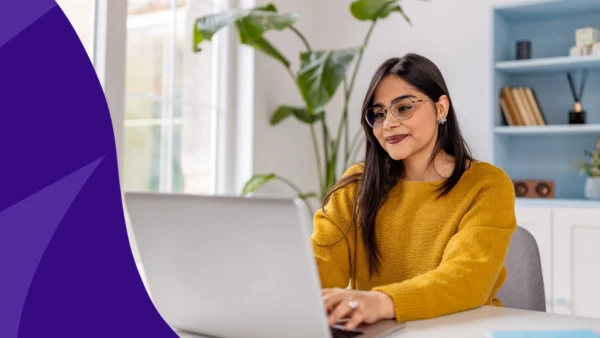 Woman smiling and looking at her computer to represent SingleCare reviews from October